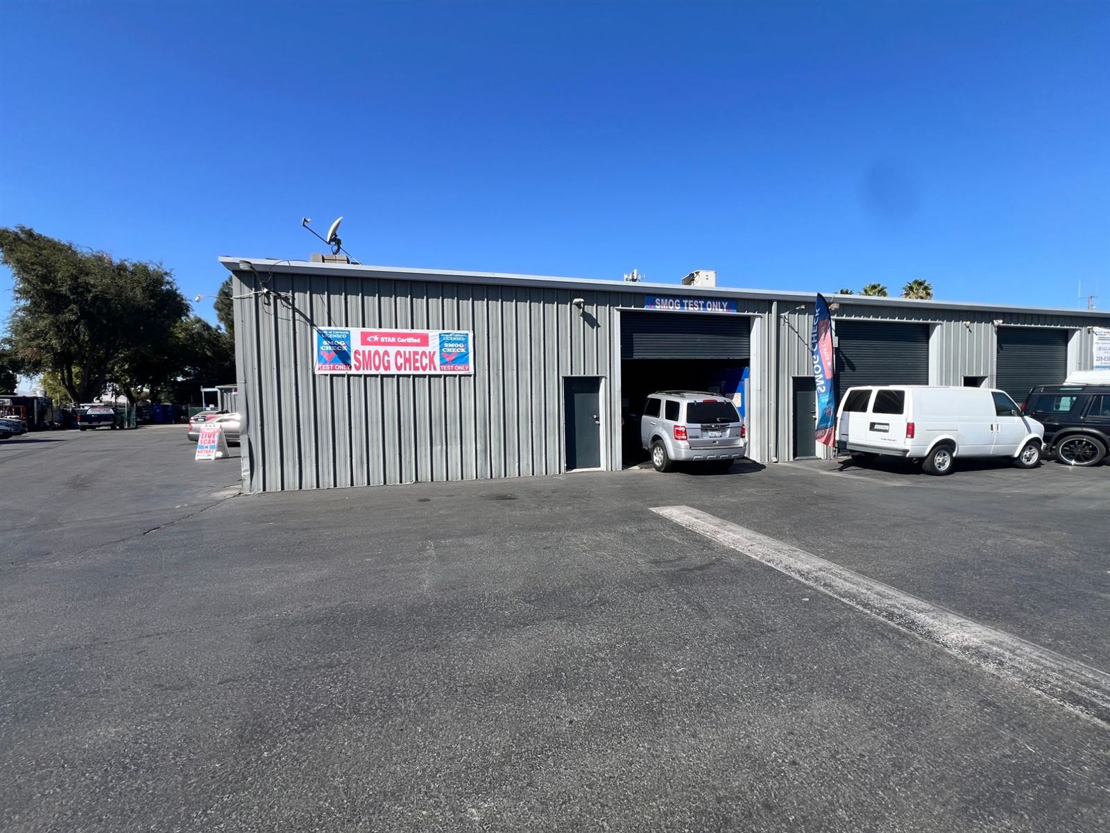 Exterior of the 6th St. & MacArthur Smog test-only smog check station in Tracy, California, with a customer vehicle in the open test bay